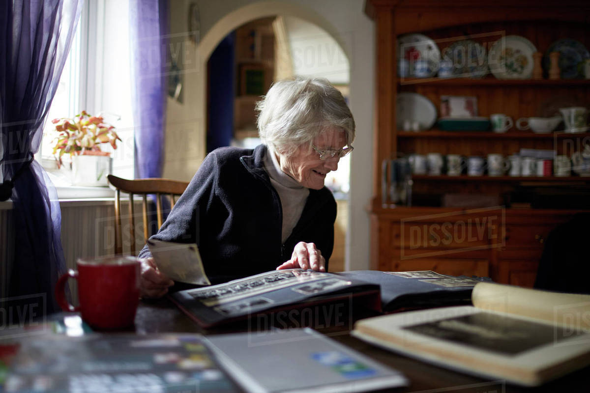 Senior woman looking through photo album at home Royalty-free stock photo