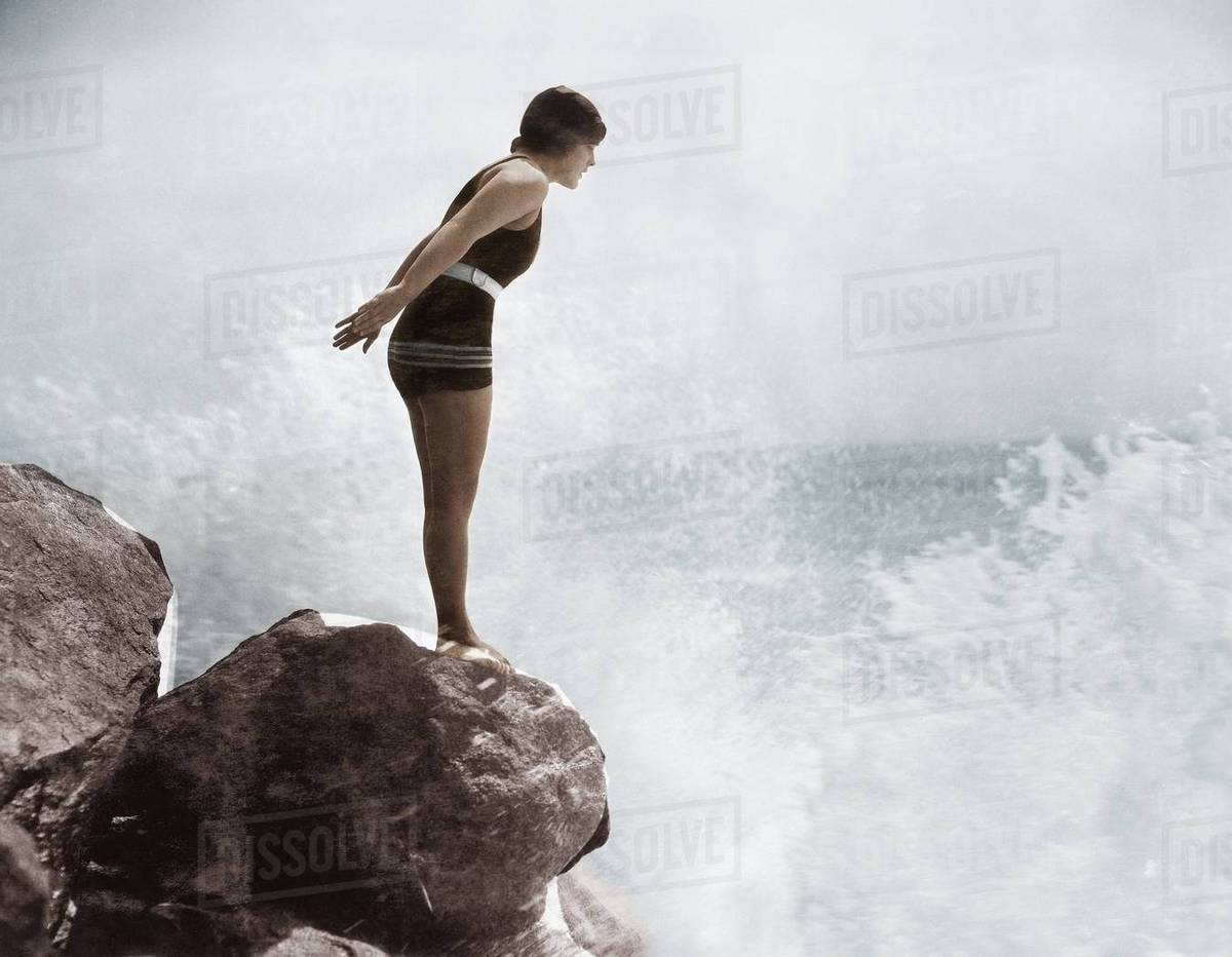 Female swimmer on rock above crashing surf Royalty-free stock photo