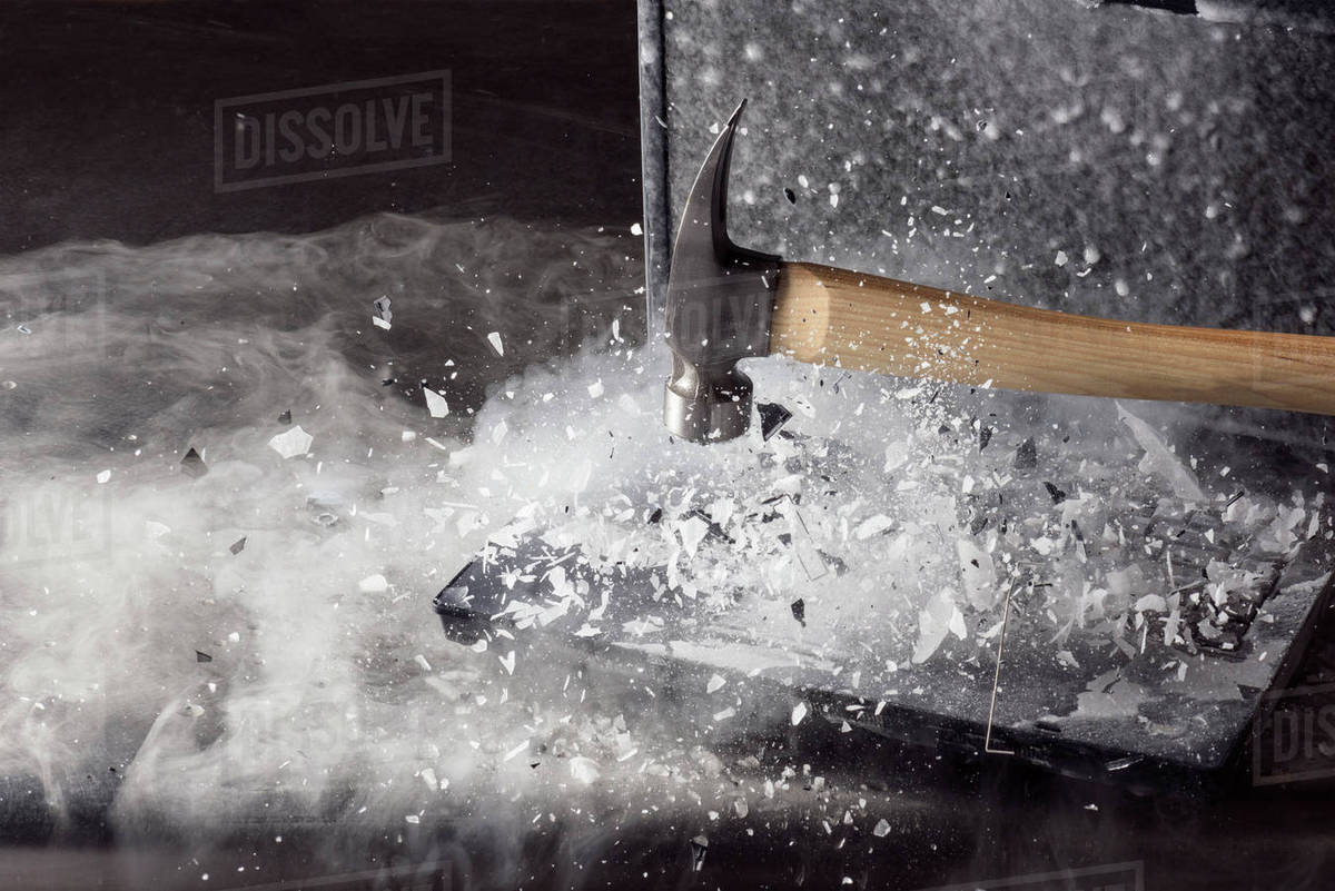Hammer breaking ice on frozen laptop Stock Photo Dissolve