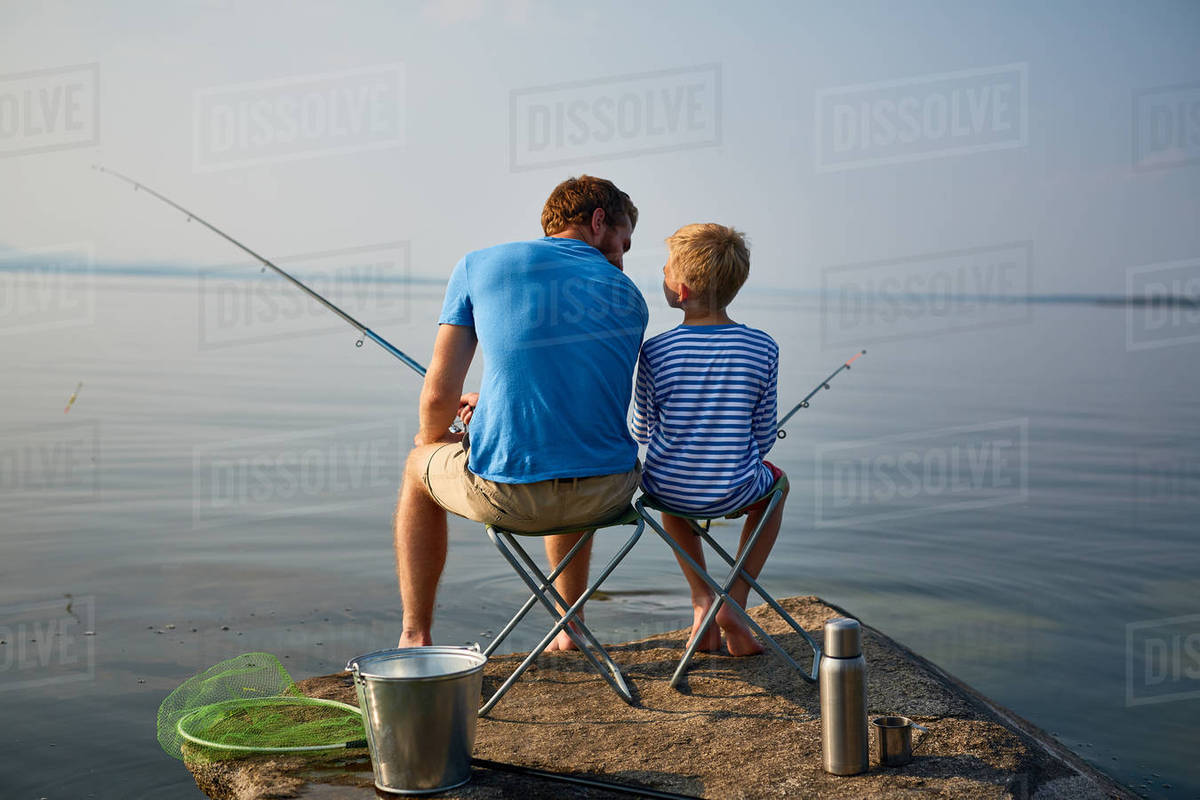 Boy and his father with rods sitting on chairs by lake Royalty-free stock photo
