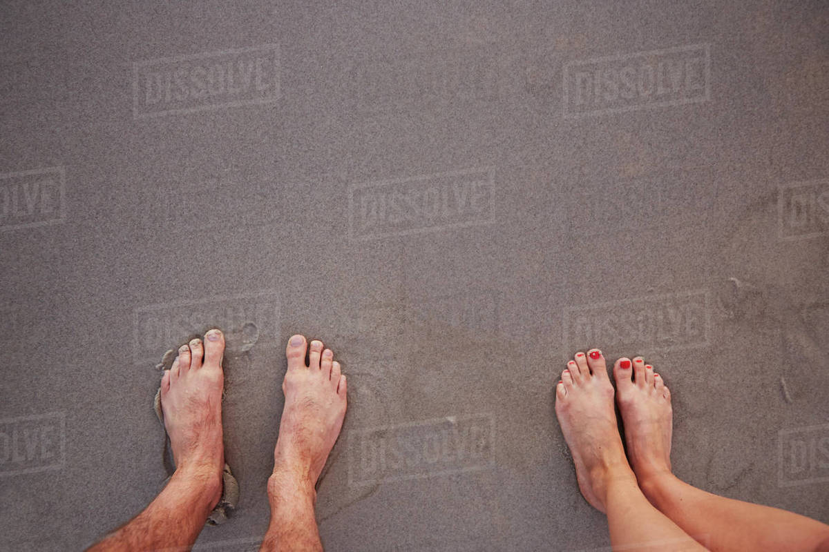 Personal perspective barefoot couple standing in wet sand on beach Royalty-free stock photo