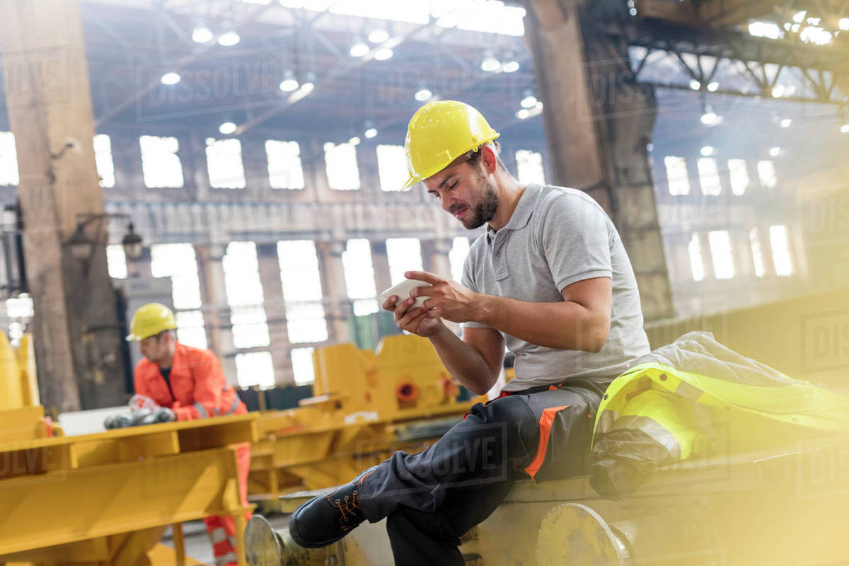 Steel worker texting with cell phone taking a break in factory - Stock ...