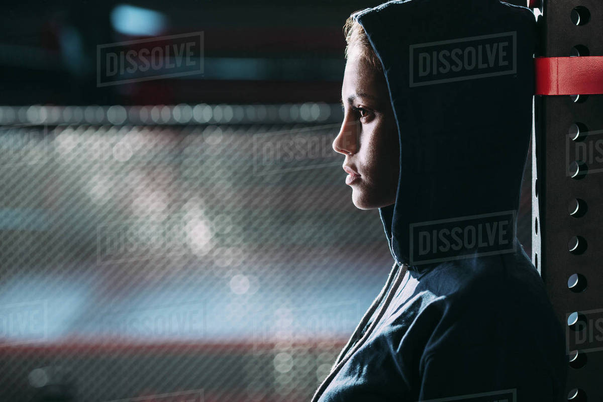 Close-up side view of woman wearing hooded shirt standing at gym Royalty-free stock photo